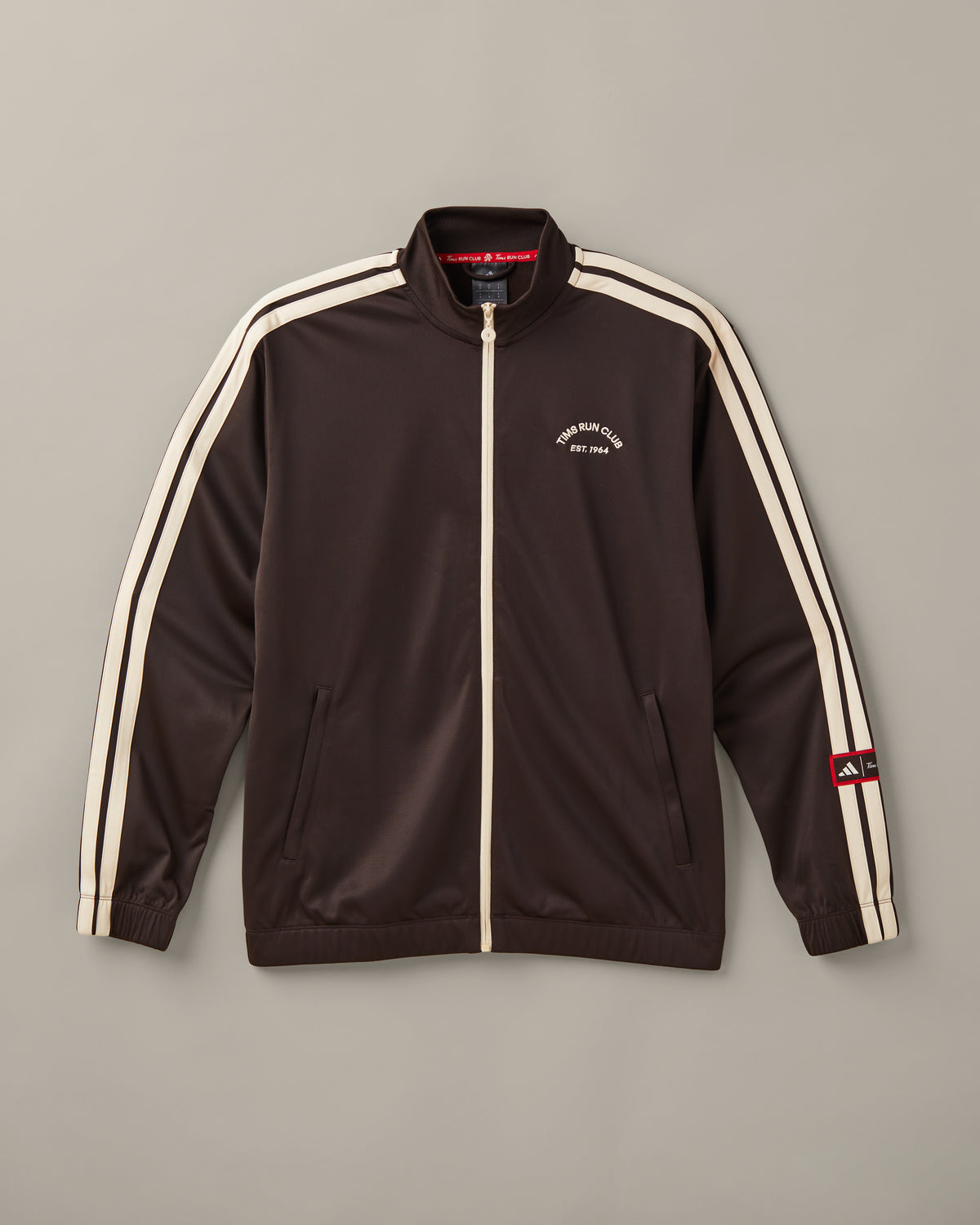 Men’s espresso-brown adidas® track top with a cream front zipper, cream 3-Stripes, and a Tims Run Club chest graphic. - Image #1