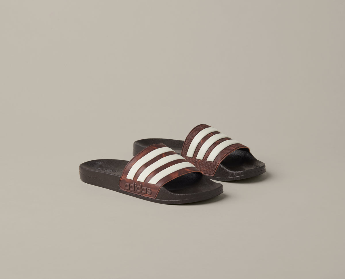 Espresso-brown adidas® Adilette Aqua slides with cream 3-Stripes across the foot straps. - Image #1