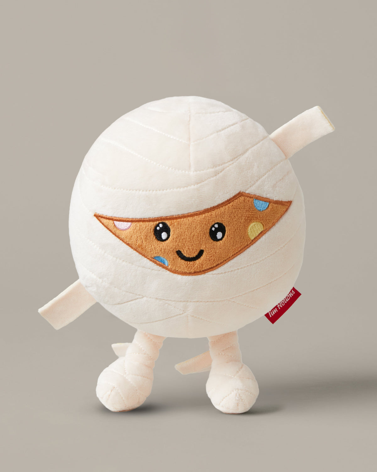 Timbits® Mummy plush with white wrapping, an embroidered face and black-and-white striped legs. | Peluche momie TimbitsMD avec bandelettes blanches, visage brodé et jambes rayées noir et blanc. - Image #1