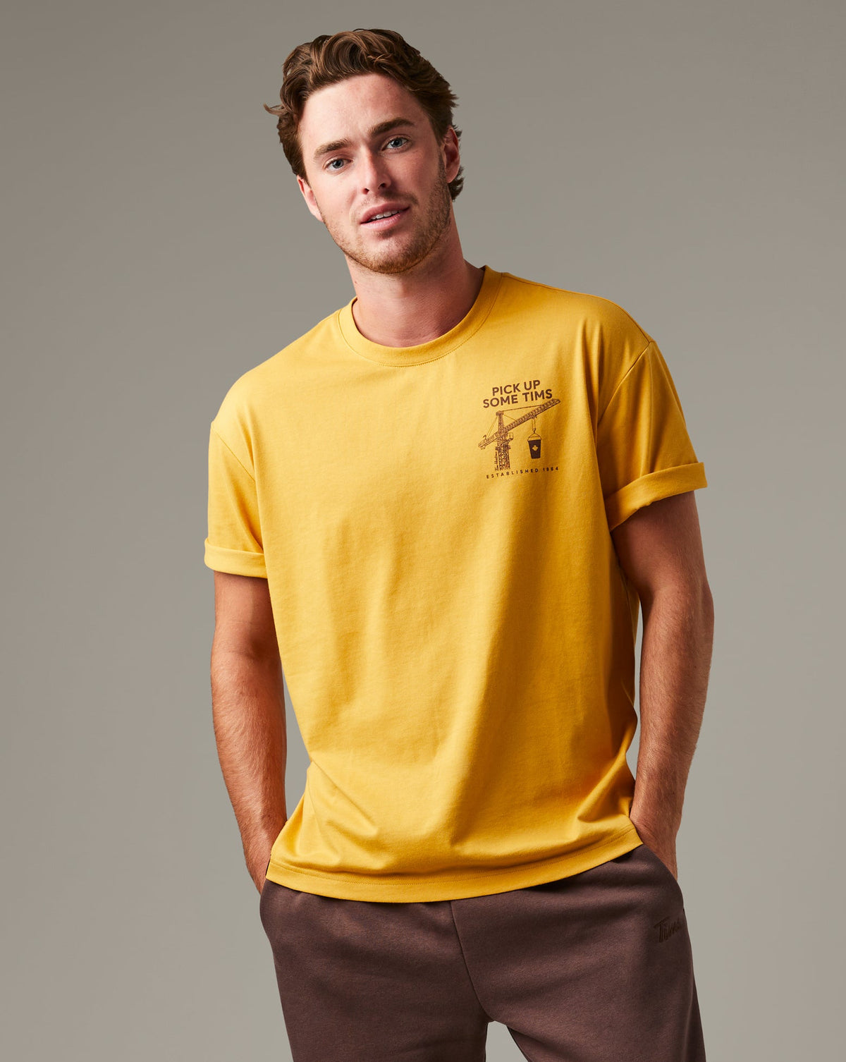 Ochre Tim Hortons crew-neck T-shirt with a small Pick Up Some Tims crane and coffee cup graphic on the chest. | T-shirt Tim Hortons ocre à encolure ronde avec une petite illustration de grue et de gobelet de café « Prendre son Tim » sur la poitrine. - Image #1