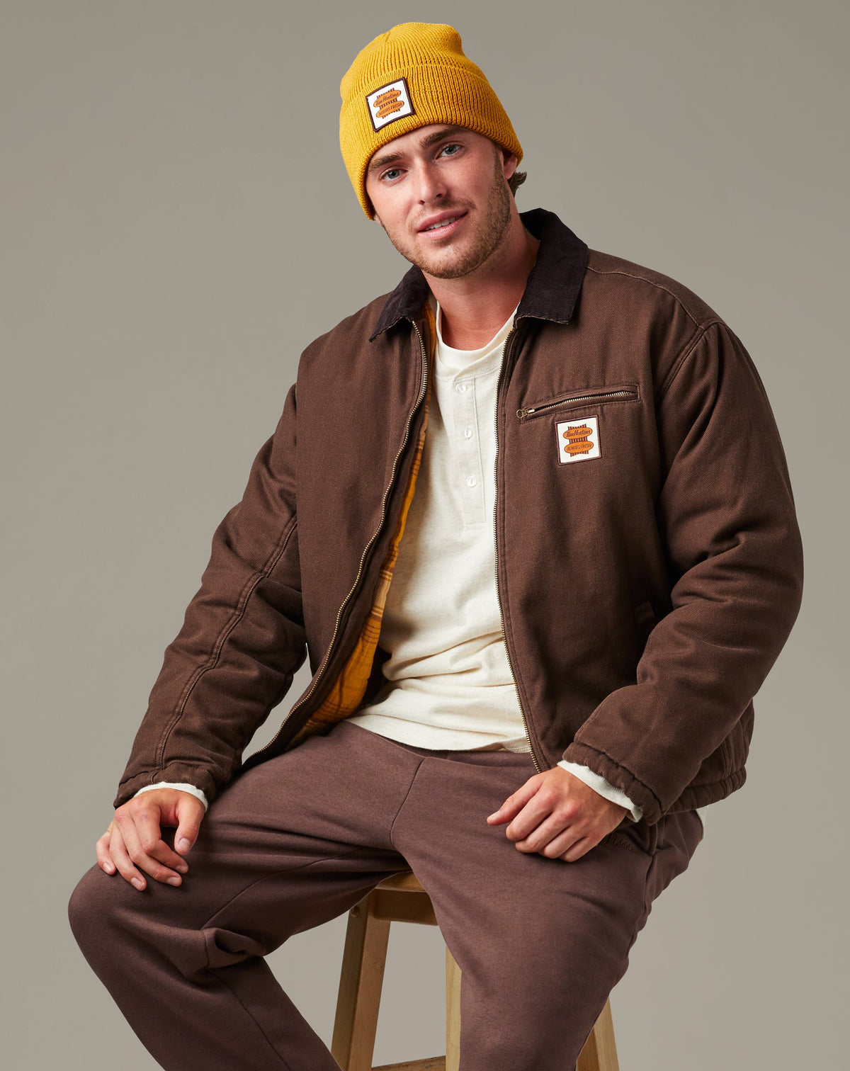 Espresso-brown Tim Hortons workwear jacket with a dark collar, front zipper, zippered chest pocket, side pockets, and retro logo patch. | Veste de travail Tim Hortons brune espresso avec col foncé, fermeture à glissière sur le devant, poche poitrine à fermeture à glissière, poches latérales et écusson à logo rétro. - Image #1