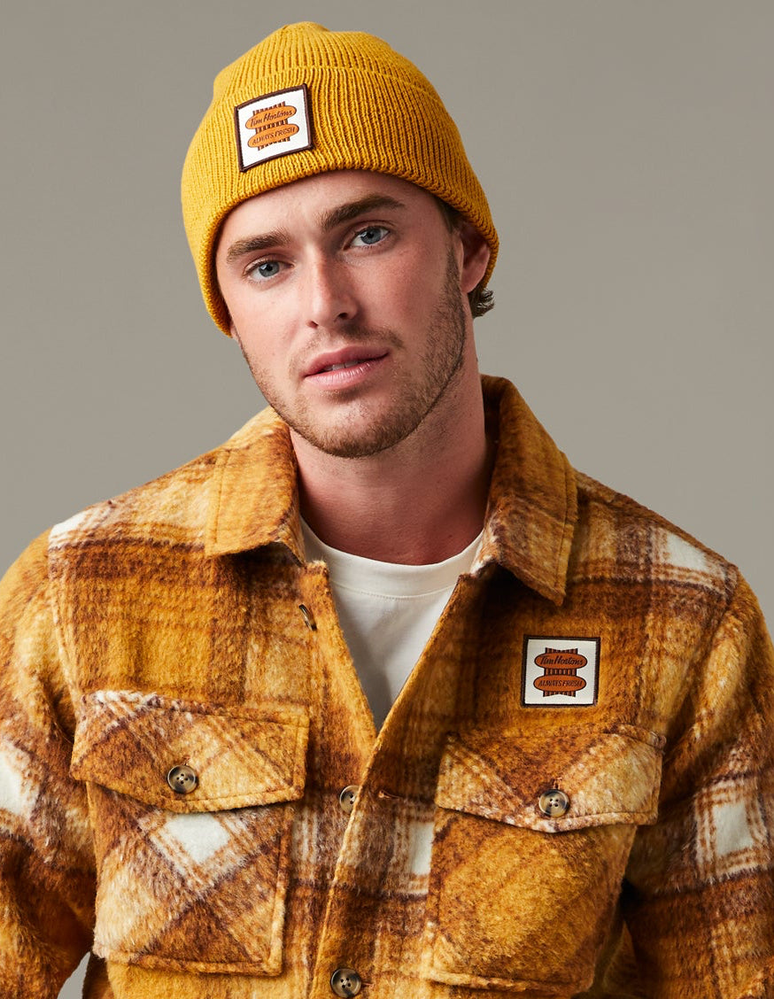 Yellow, brown, and cream plaid Tim Hortons shacket with a button front, two flap chest pockets, and a small logo patch. | Surchemise Tim Hortons à carreaux jaunes, bruns et crème, avec fermeture à bouton sur le devant, deux poches poitrine à rabat et un petit écusson à logo. - Image #1